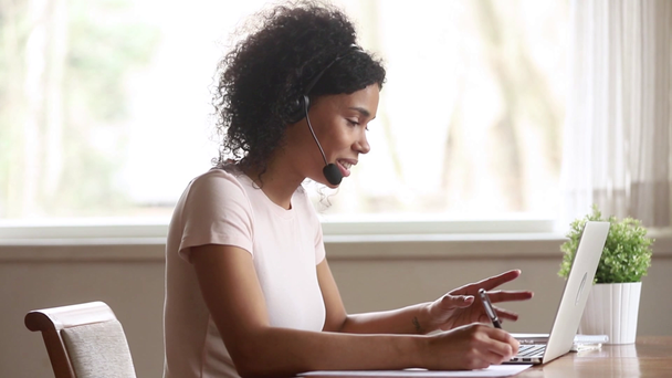 Африканський жіночий вчитель Skype носіння гарнітури Говорячи дивлячись на ноутбук - Кадри, відео
