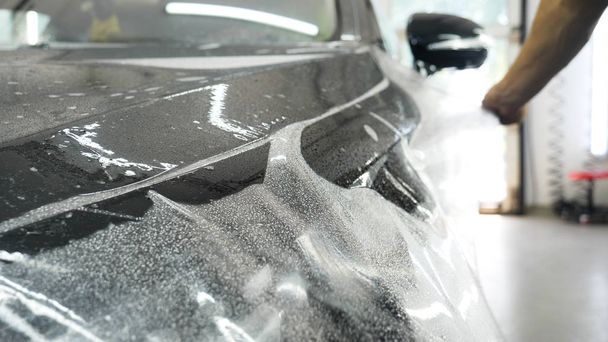 Close up to PPF installation process on a front headlight and hood. PPF is a Paint Protection Film which protect paint from scratches and stone chips. Concept of: Guard, Protect, Car, New, Work. - 写真・画像