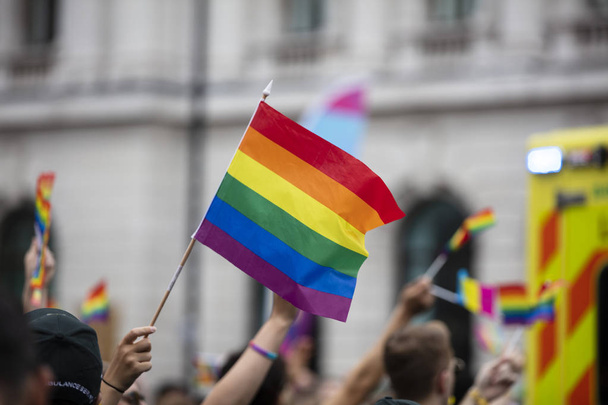 A spectator waves a gay rainbow flag at an LGBT gay pride march in London - Foto, Bild