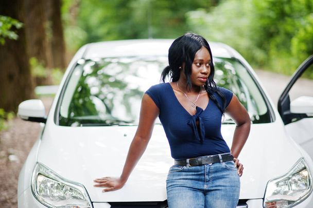 African american woman posed against white car in forest road. - Photo, Image