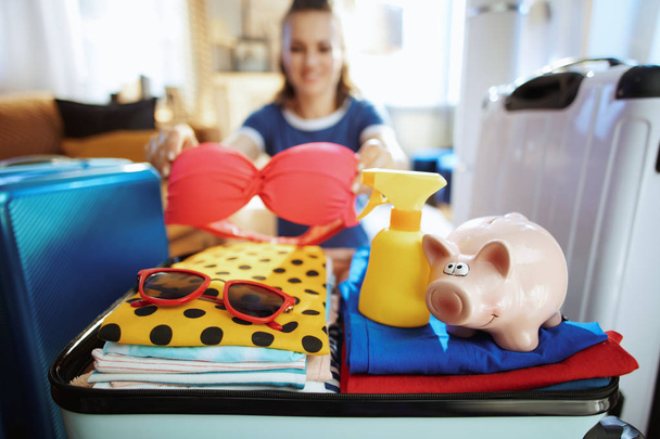 Closeup on happy woman with piggy bank calculates summer budget - Foto, imagen