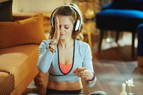 young woman watching yoga tutorial on internet via smartphone - Fotó, kép
