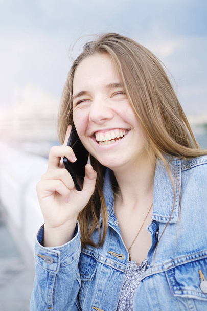 τεχνολογία, την επικοινωνία και τους ανθρώπους έννοια-ευτυχής νεαρή γυναίκα που καλεί το smartphone και γέλιο στο δρόμο - Φωτογραφία, εικόνα