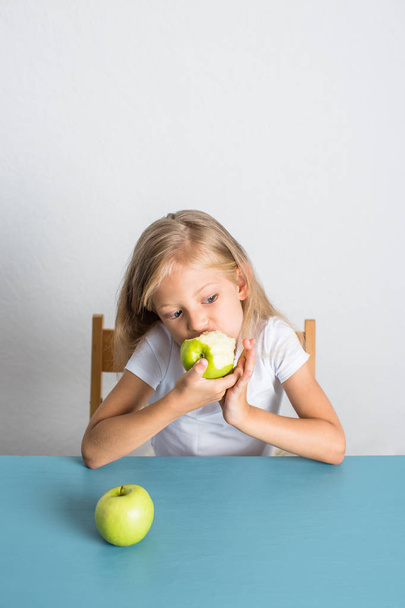 Beautiful girl 7 years old eats an apple - Zdjęcie, obraz