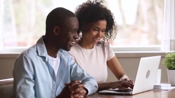 Euphoric african couple looking at laptop excited by online win - Imágenes, Vídeo
