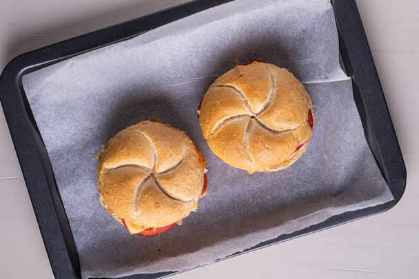 Kaksi kotitekoista hampurilainen Wien Kaiser leipää sämpylä roll kanan liha tomaatti sinappi majoneesi leivinpaperilla pergamentti paperi valkoinen tausta
 - Valokuva, kuva