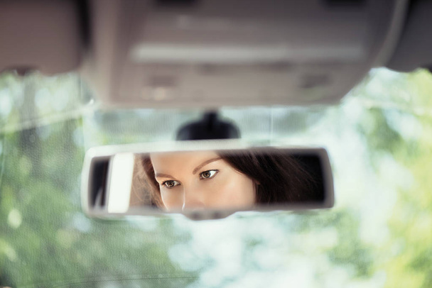Reflection of a beautiful young woman face in the car rear view mirror. concept - Foto, Imagem