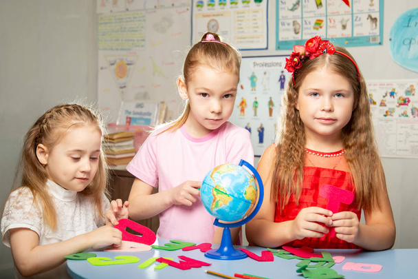 Los niños aprenden nombres de países en inglés. las niñas están sosteniendo un globo
. - Foto, imagen