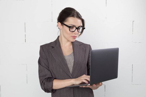 Business woman in glasses and suit with a laptop in hand on white background. - Foto, Bild