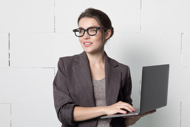 Business woman in glasses and suit with a laptop in hand on white background. - Foto, Imagen