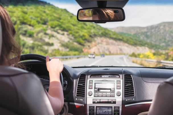 少女はカナリア諸島のテネリフェ島の道路を運転しています。フロントガラス、道路、運転手の車の後部座席からの眺め - 写真・画像
