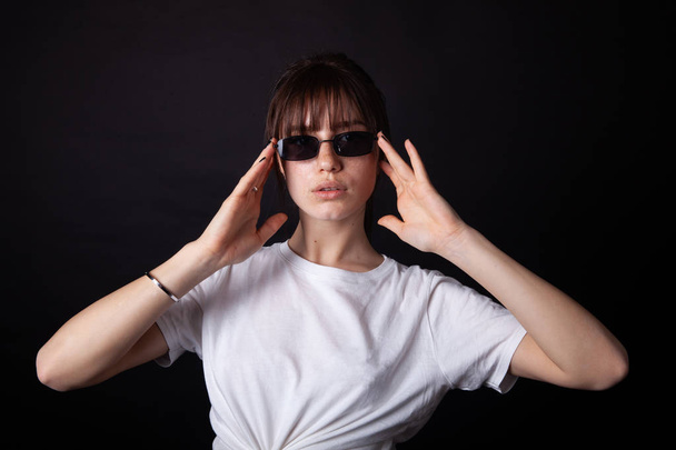 Caucasian Girl in white shirt with black sunglasses posing in the studio - Foto, afbeelding