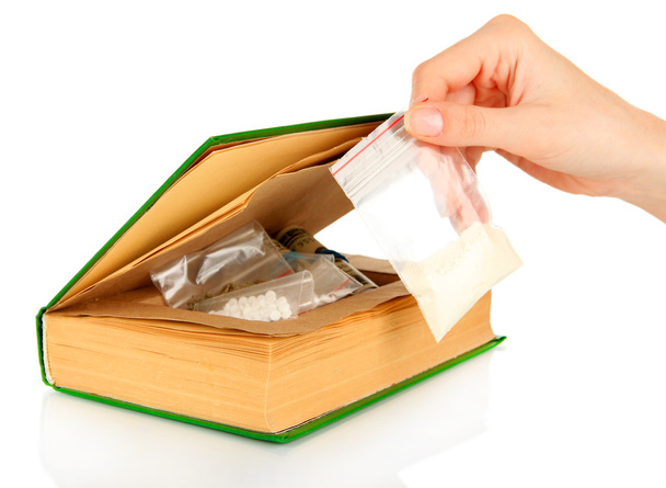 Hand holding narcotics near book-hiding place isolated on white - Φωτογραφία, εικόνα