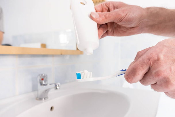 Person putting toothpaste on toothbrush - Fotoğraf, Görsel