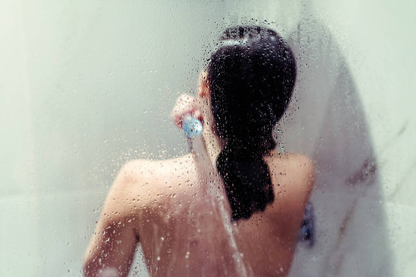 Naked beautiful woman taking a shower behind wet misted glass. - Foto, immagini