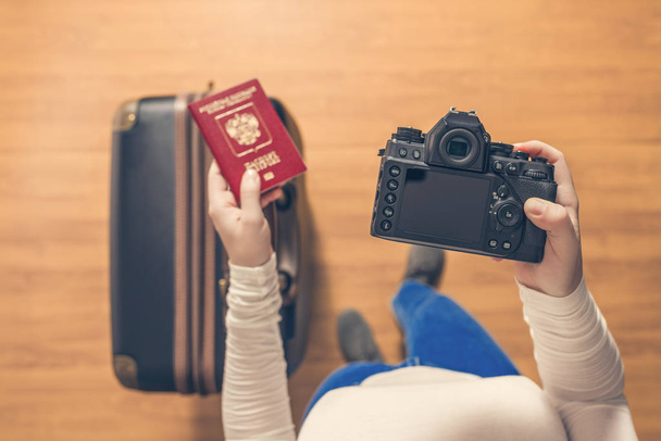 Bovenaanzicht van een meisje met een koffer en een Russisch paspoort wandelen op de luchthaven naar paspoortcontrole. - Foto, afbeelding