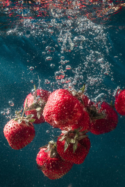 fresh summer strawberries. Strawberries in water. spray, berries, red and blue. still-life. background. abstraction. food. photo of food. Strawberry berries fall into the water. lovely fresh taste of summer. - Fotó, kép