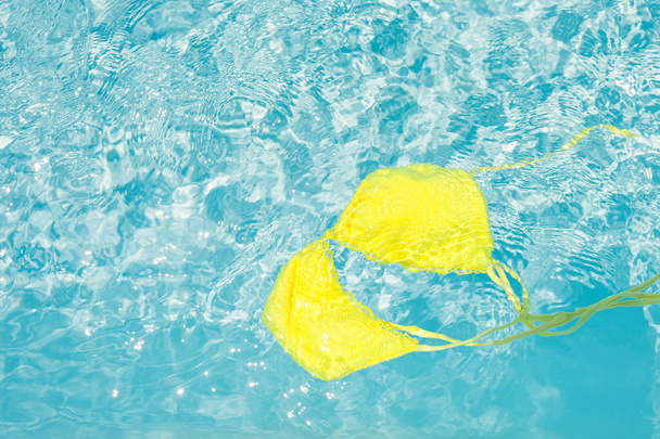 Желтое бикини в чистой голубой воде бассейна
. - Фото, изображение