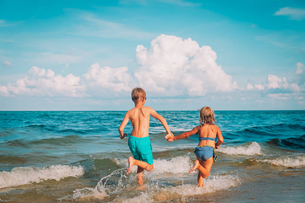 χαρούμενο αγόρι και κορίτσι τρέχουν να παίξουν στην παραλία - Φωτογραφία, εικόνα