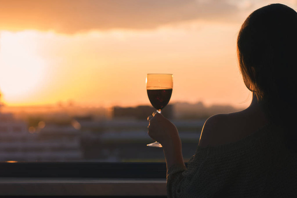 Silhouette of woman with glass of red wine  - 写真・画像