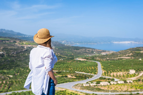 Woman in tourist clothes and straw hat standing on top of a mountain. Concept - Photo, image