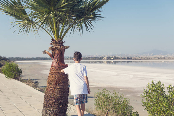 A boy in shorts and a T-shirt near the salt lake in Larnaca. Cyprus - Φωτογραφία, εικόνα