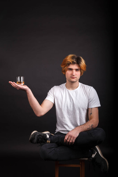 Jeune adulte caucasien aux cheveux blonds tenant du whisky à la main
 - Photo, image