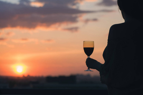 Silhouette of woman with glass of red wine  - 写真・画像
