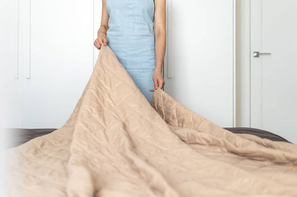 Housemaid nő, hogy ágyban belül világos és világos hálószoba - Fotó, kép