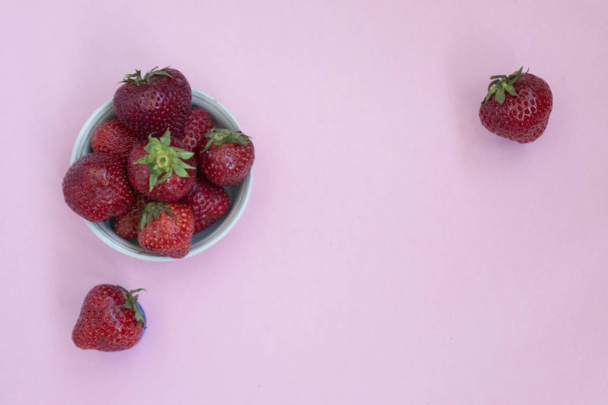 Ripe red strawberries in a plate. Pink background. Foods with vitamins. - Foto, Imagen