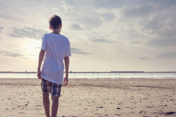 A boy in shorts and a T-shirt near the salt lake in Larnaca. Cyprus - Φωτογραφία, εικόνα
