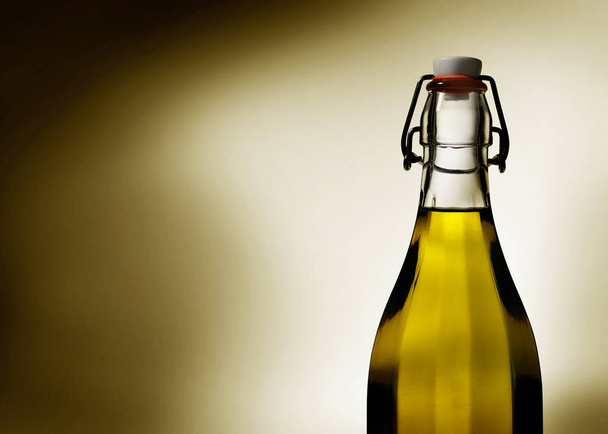 Dramatic light glows through olive oil in a clear glass bottle - Photo, Image