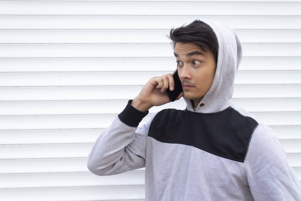 Yüzünde şaşkınlıkla telefonda konuşan genç bir adamın portresi. - Fotoğraf, Görsel