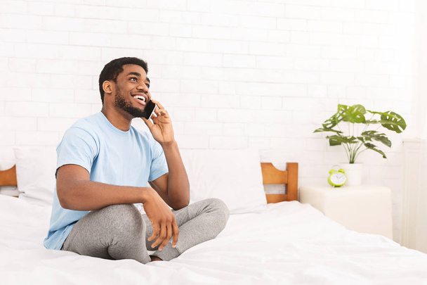 Veselá afroamerické chlap mluví o telefonu v posteli - Fotografie, Obrázek