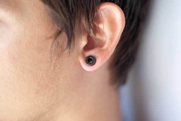 Piercing im Ohr, Tunnel in den Ohren eines jungen Mannes - Foto, Bild
