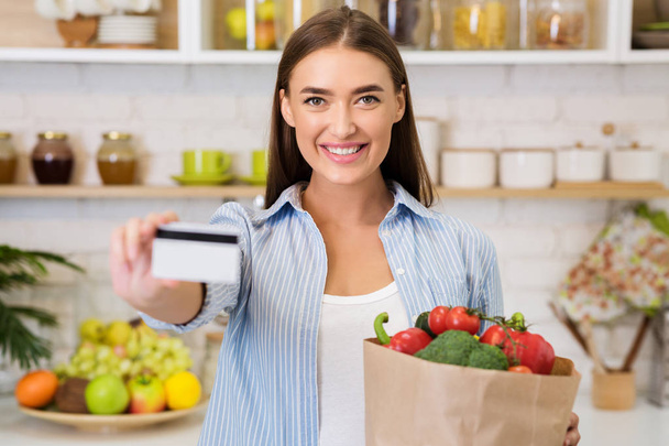 Kobieta z kartą kredytową i papierową torbą z warzywami - Zdjęcie, obraz