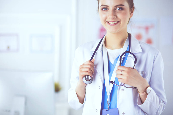 Portret van een jonge vrouwelijke arts met witte jas in het ziekenhuis - Foto, afbeelding