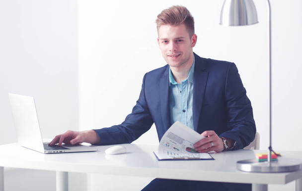 Business man sitting at white table with a white laptop on white background - Photo, image