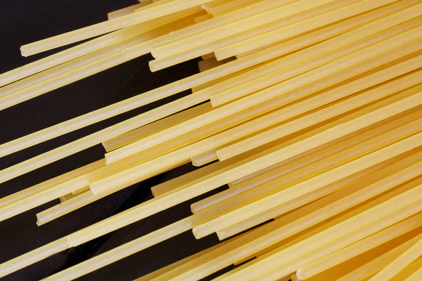Spaghettis dorés non cuits reposent sur un fond en bois noir. Mini
 - Photo, image