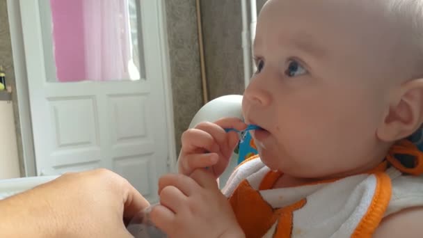 Mooie baby drinkt water door een plastic stro in een flat in de zomer in slo-mo - Video