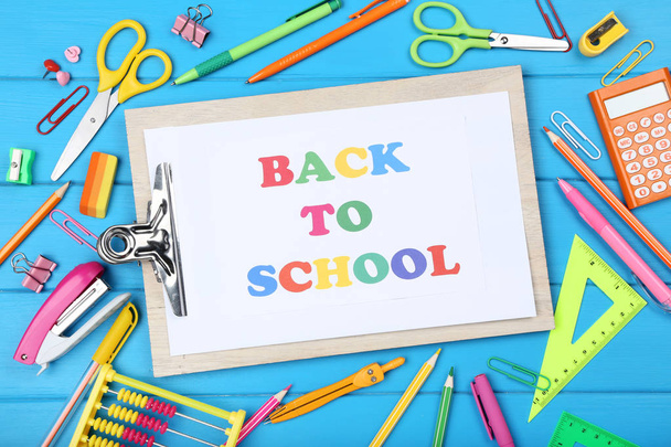 Text Back To School on clipboard with stationery on blue wooden  - Fotoğraf, Görsel