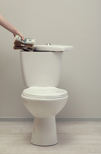 Hand hides money in toilet tank in a bathroom - Photo, image