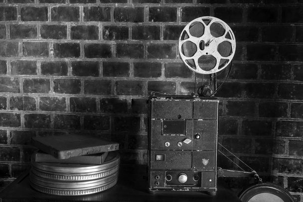 レンガの壁の背景に古い映画プロジェクターの写真。古いスタイルの映画プロジェクター、静止画、クローズアップ. - 写真・画像