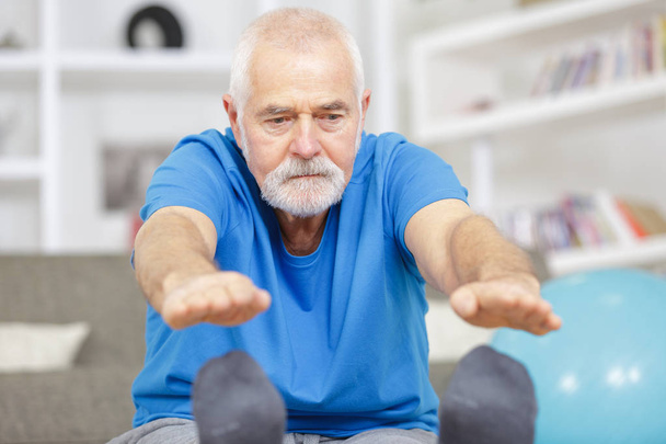 sporty elderly guy practicing yoga indoors - Zdjęcie, obraz