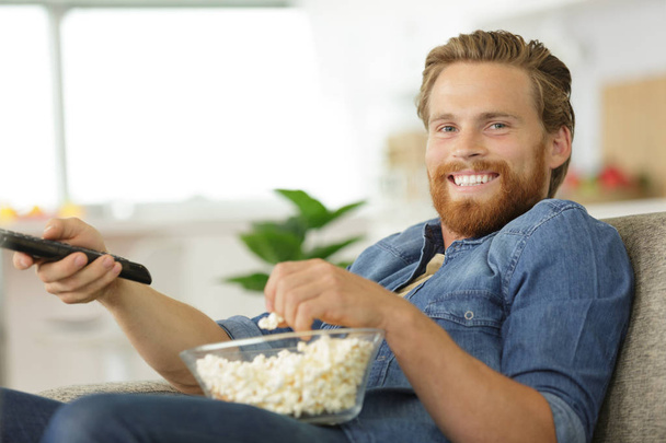 man with a bowl of popcorn watching tv - Zdjęcie, obraz