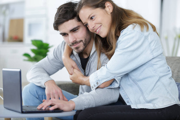 couple embracing while looking at laptop together - Fotó, kép