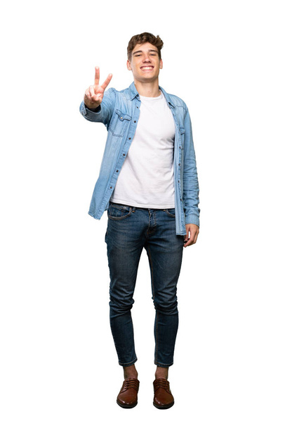 A full-length shot of a Handsome young man smiling and showing victory sign over isolated white background - Foto, afbeelding