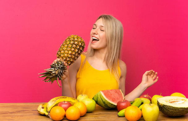 Jeune femme avec beaucoup de fruits tenant un ananas
 - Photo, image