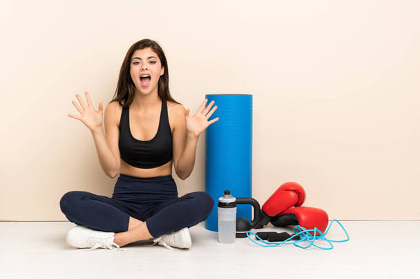 Teenager sport girl sitting on the floor with shocked facial expression - Photo, Image