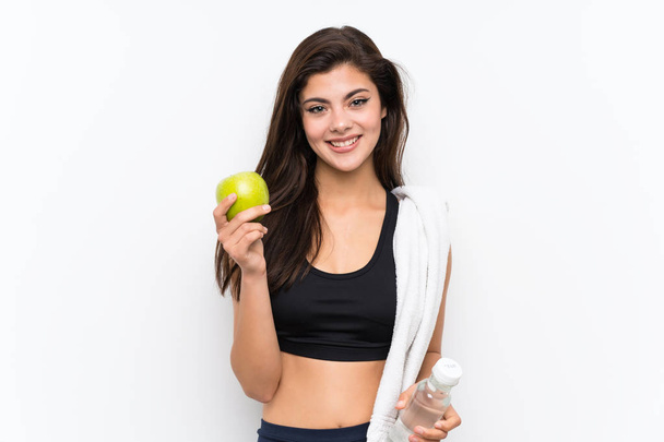 Teenager sport girl over isolated white background with an apple and a bottle of water - Foto, Bild